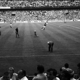 Classic soccer match with players on field and packed stadium.