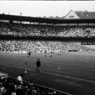 Black-and-white soccer match with packed stadium.