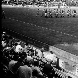 Historical football match with players on field.