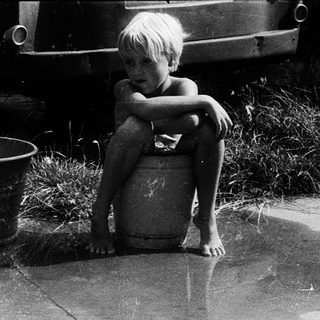 Two children playing in shallow water with inflatable ring.