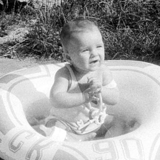 Baby sitting in outdoor inflatable pool.