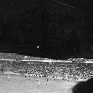 Black-and-white soccer match with packed stadium.