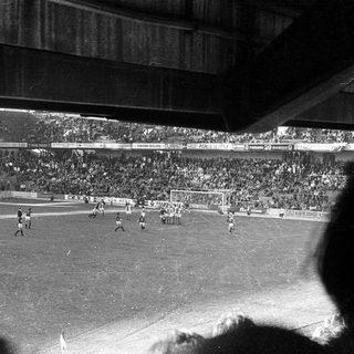 Black-and-white stadium football match in progress.