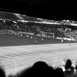 Black-and-white stadium football match with packed crowd.