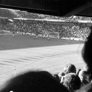 Black-and-white stadium match with packed crowd.