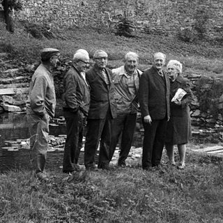 Group of people gathered outdoors near a pond.