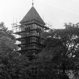 Historic stone tower under restoration with scaffolding.