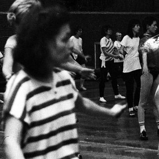 Children dancing indoors during a gym class.
