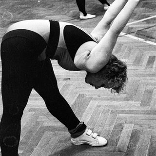 Woman performing forward bend stretch indoors.