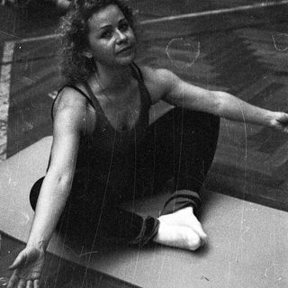 Woman stretching on yoga mat indoors.
