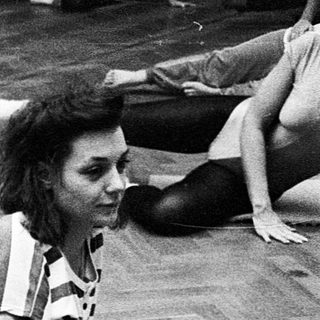 Women practicing ballet stretches in a studio.