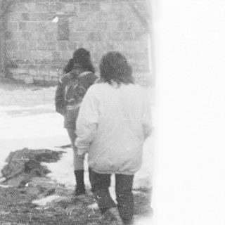People walking in snowy, foggy outdoor setting.