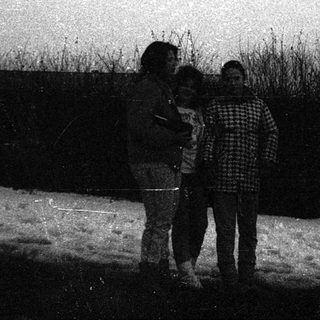 Four people standing outdoors in winter snow.