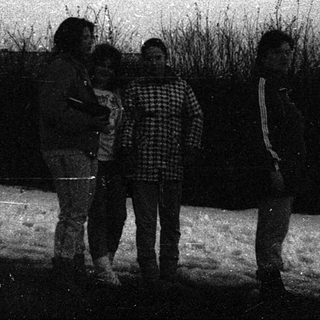 Four people standing outdoors in winter snow.