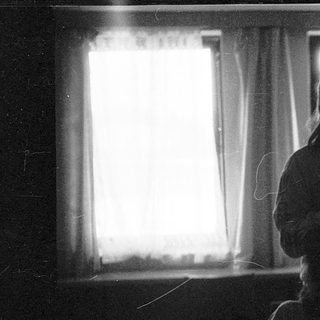 Two people sitting indoors near a window.