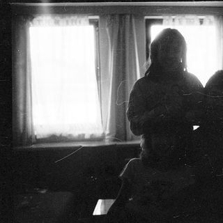 Two people sitting indoors near a window.