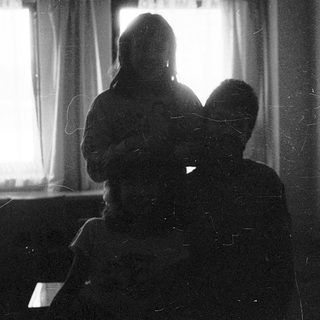 Two people sitting indoors near a window.