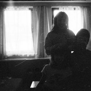 Two people sitting indoors near a window.