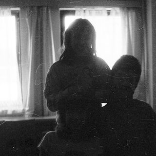 Two people sitting indoors near a window.