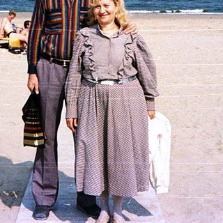 Two people posing on a beach under clear skies.