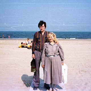 Two people posing on a beach under clear skies.