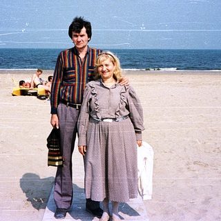 Two people posing on a beach under clear skies.
