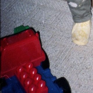 Young child in overalls holding yellow fabric.