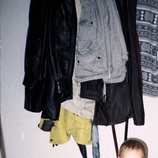 Baby standing in hallway mirror wearing diaper and holding stuffed animal.