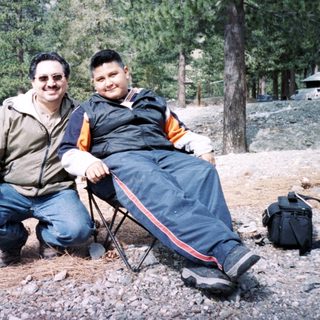 Two men posing outdoors in winter forest setting.