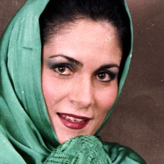 Woman wearing traditional green headscarf and lace shawl.