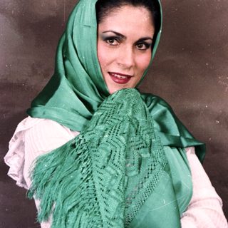 Woman wearing traditional green headscarf and lace shawl.