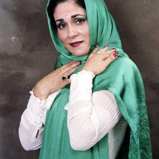 Woman wearing green headscarf and white sleeves.