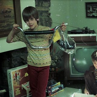 Two boys playing with plastic bag indoors.