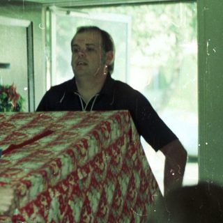 Two men carrying a large, patterned mattress indoors.