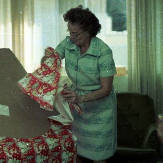 Woman ironing near floral-patterned couch.