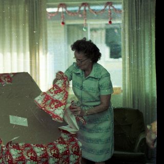 Woman ironing near floral-patterned couch.