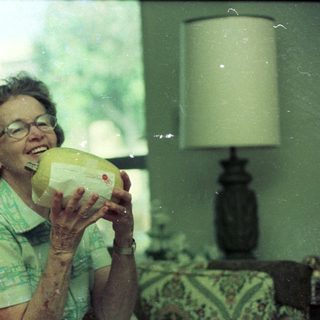 Woman drinking from a pineapple indoors.