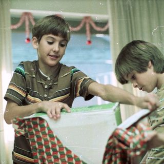 Two boys playing with festive ribbon indoors.