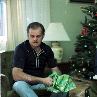 Couple opening holiday gifts by Christmas tree.
