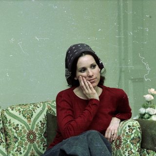 Woman in red sweater resting thoughtfully indoors.