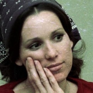 Woman in red sweater resting thoughtfully indoors.