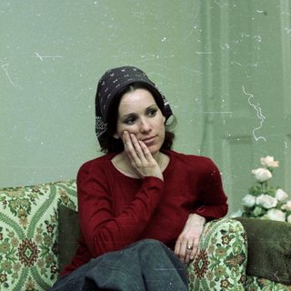 Woman in red sweater resting thoughtfully indoors.