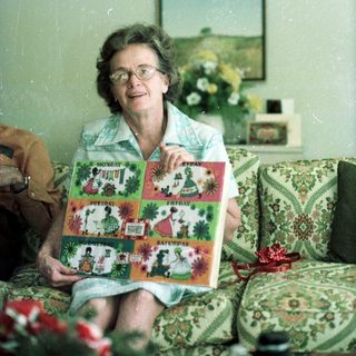 Woman proudly holding colorful quilted Christmas stockings.