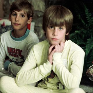 Two young boys sitting indoors, posing solemnly.