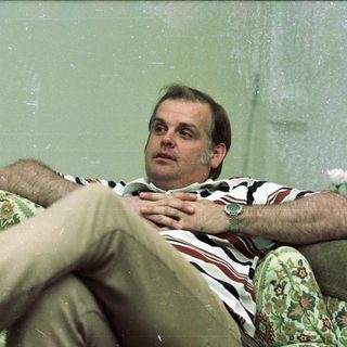 Man relaxing on floral-patterned armchair indoors.