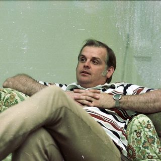 Man relaxing on floral-patterned armchair indoors.