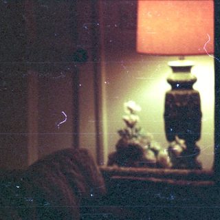 Blurred interior scene with person near lit lamp.