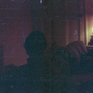 Blurred interior scene with person near lit lamp.
