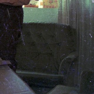 Two people playing pinball in a dimly lit room.