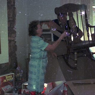 Two people playing pinball in a dimly lit room.